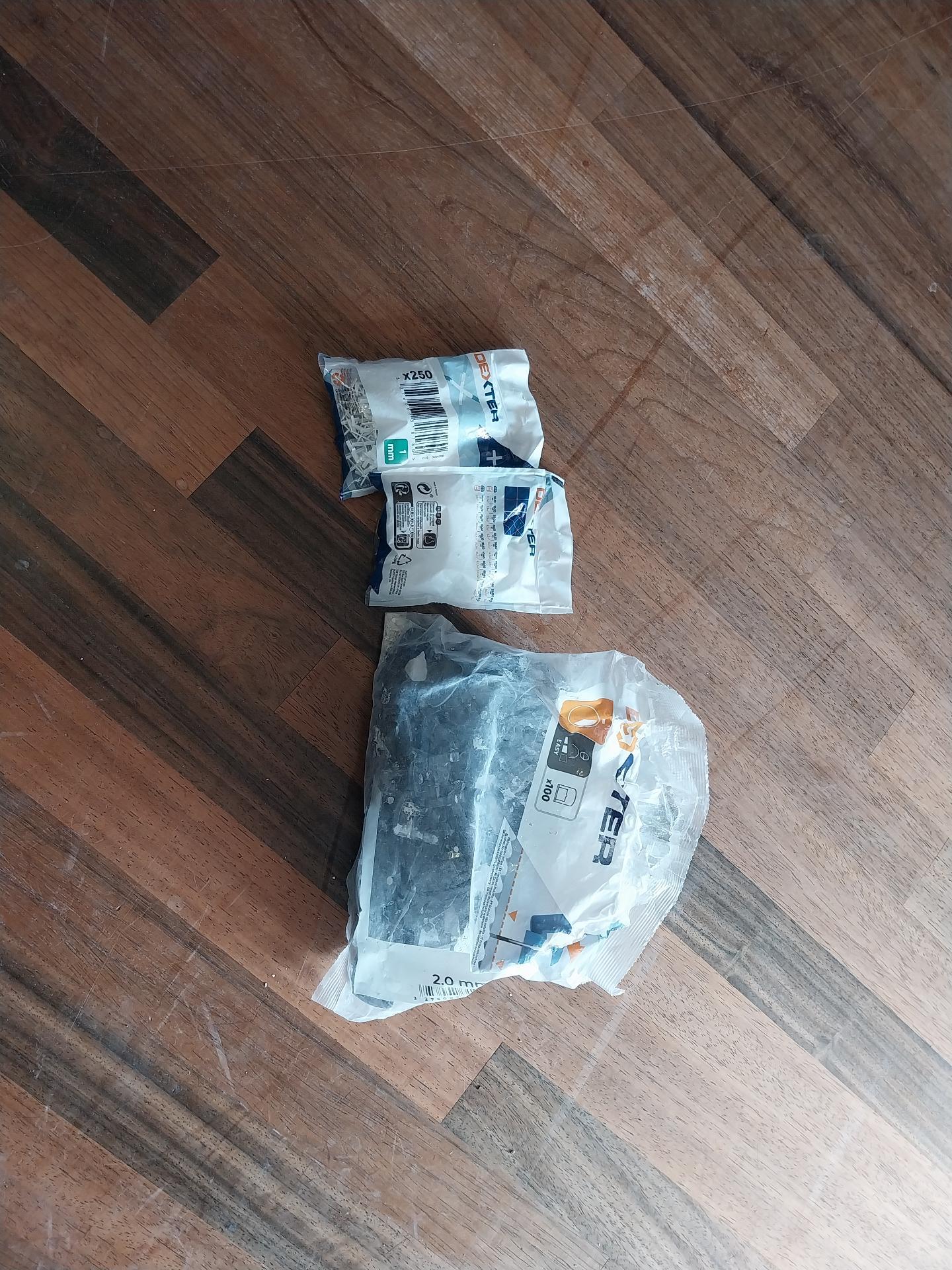 Due sacchetti di distanziatori a crocetta per piastrelle da 1 mm e un'altro sacchetto di materiale per posa di piastrelle