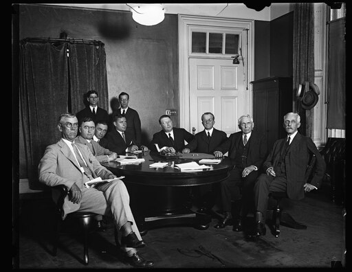 Group at table; Frank Kellogg and Andrew Mellon at right.