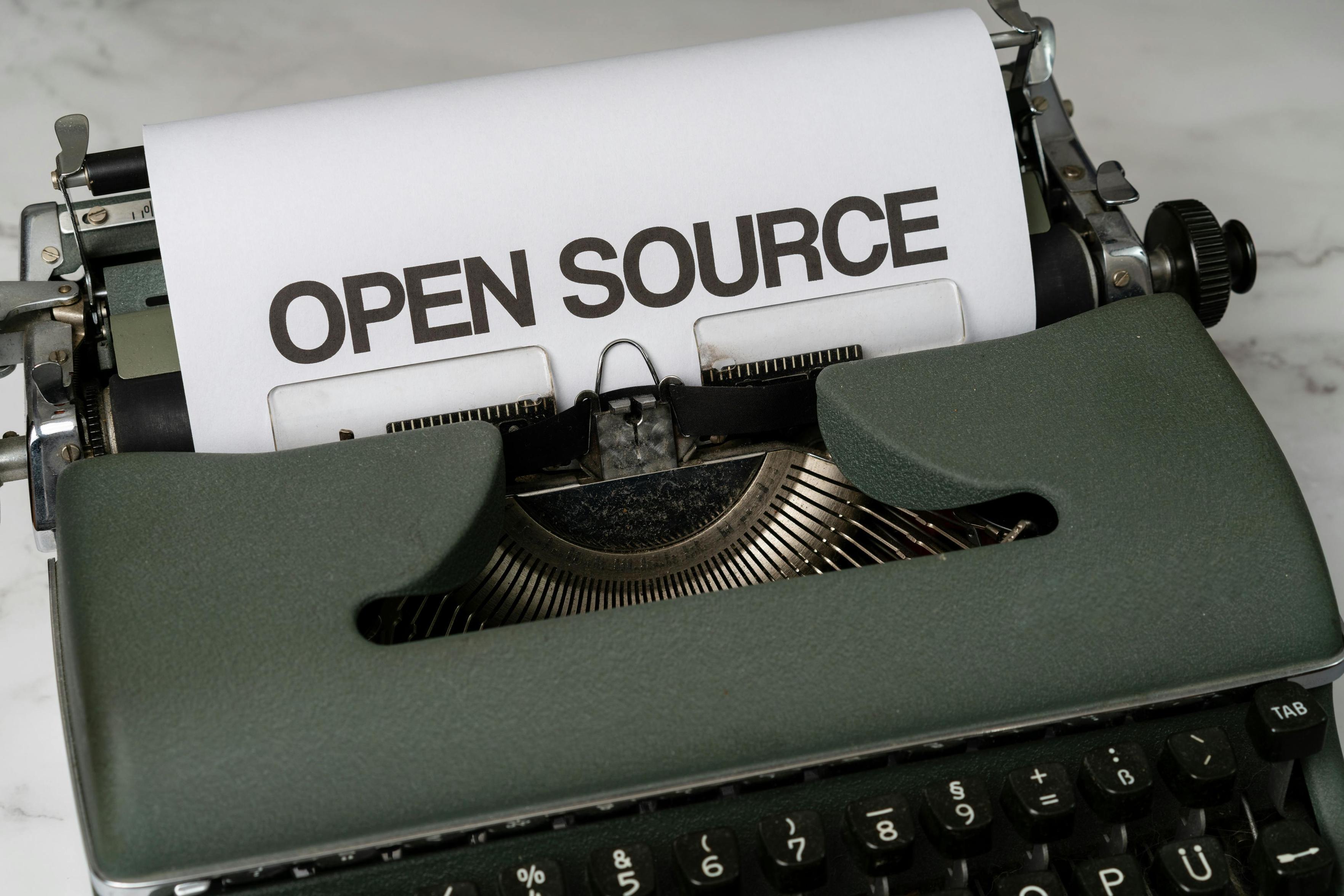 A typewriter with paper coming out, large words 'Open source' on the paper.